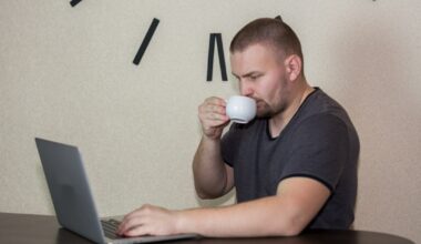 a man drinking a cup of coffee while using a laptop